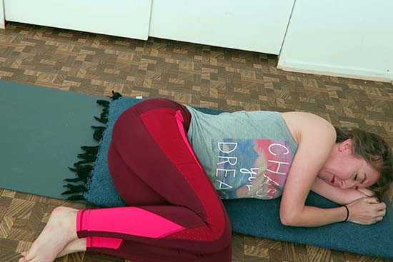 yoga teacher lying on mat in fetal position