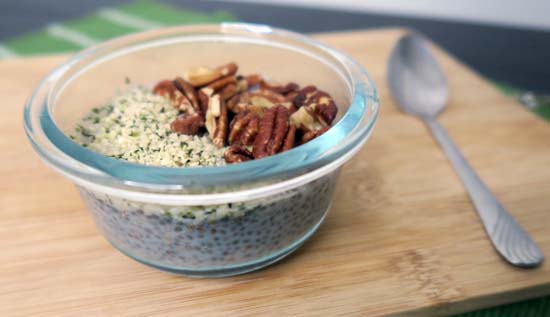 chia pudding in a glass dish on a wood board, with a spoon.