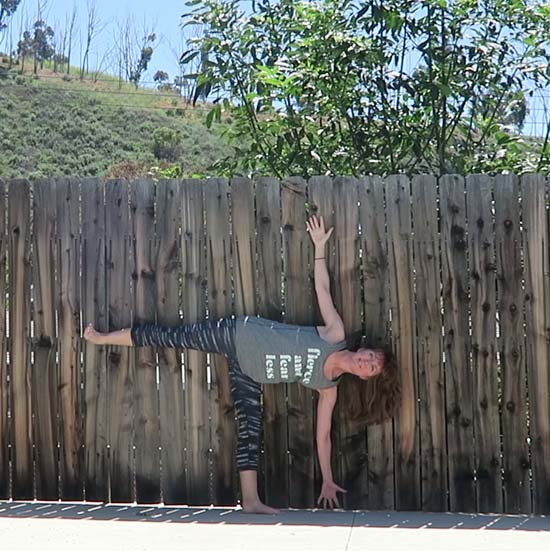 Yoga teacher using fence as yoga prop