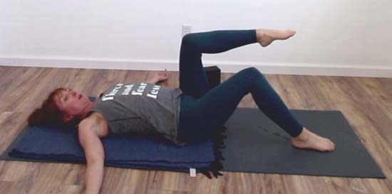 Pilates instructor showing single leg table top exercise displaying arched back