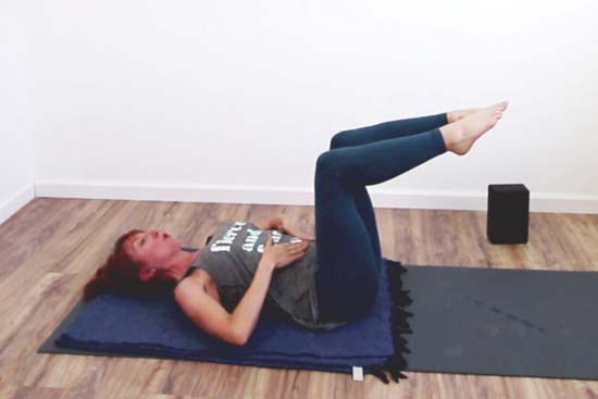 Pilates instructor showing single leg table top exercise knees bent