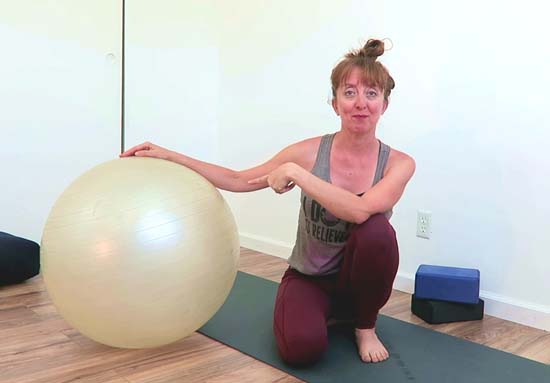 yoga teacher with a yoga ball on a yoga mat