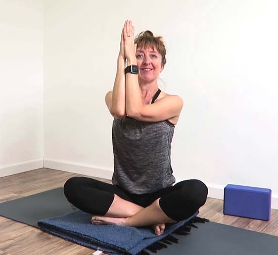 Yoga teacher demonstrating eagle arm modification with the forearms together 