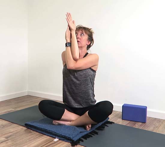 Yoga teacher demonstrating eagle arm modification with the forearms twisted together 
