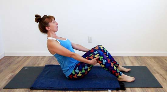 yoga teacher seated on mat 