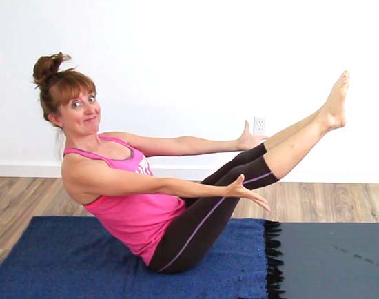 Yoga teacher holding boat pose with straight legs