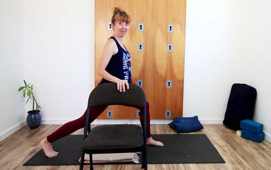 yoga teacher in standing yoga pose with chair support