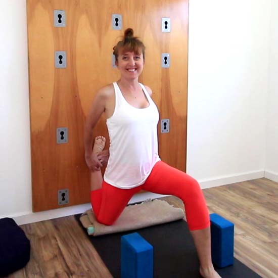 yoga teacher in quad stretch against a yoga wall