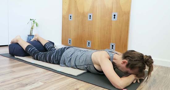 face down savasana with feet supported on bolster