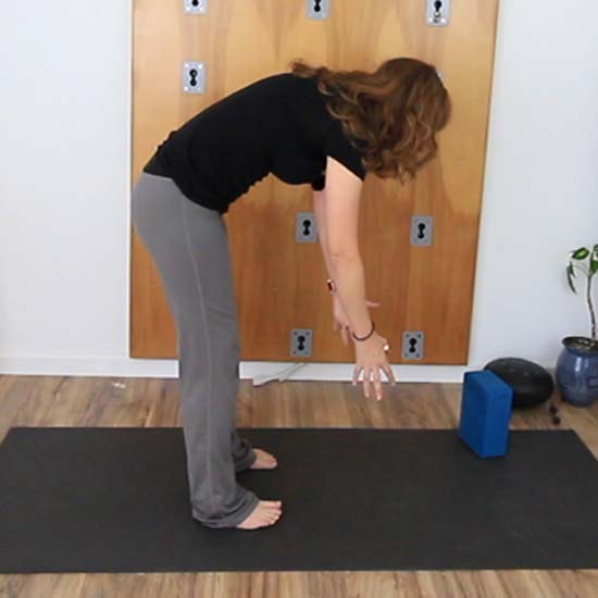 yoga teacher demonstrating forward fold done incorrectly folding from mid-back