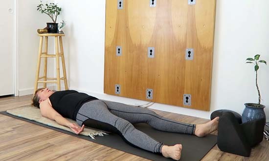 yoga teacher lying on her back on a yoga mat