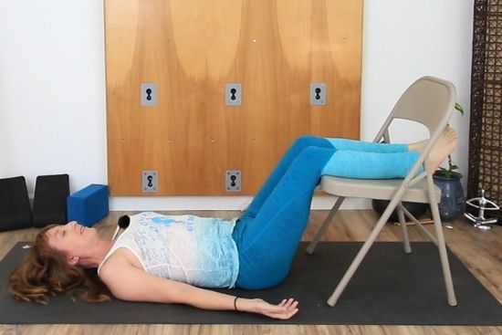 restorative savasana, lying supine with legs supported on chair