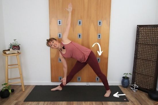 yoga teacher demonstrating triangle pose at the wall