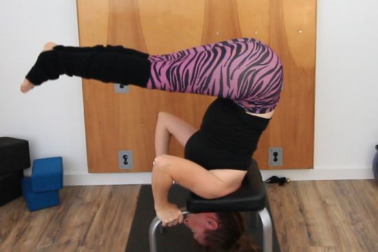 yoga teacher demonstrating exercises in a headstand bench