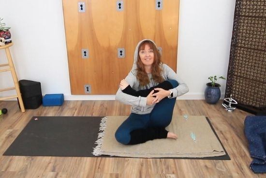 Yoga teacher demonstrating yoga for cold days "rock the baby" poses on a yoga mat
