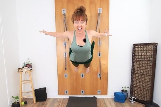yoga teacher suspended from yoga wall