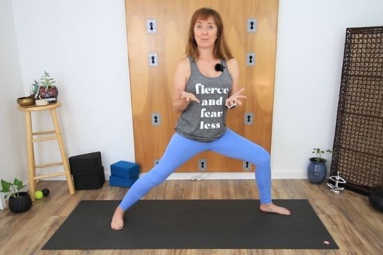 yoga teacher standing on a yoga mat in warrior 2