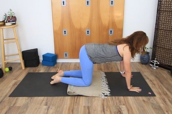 yoga teacher on a yoga mat with blanket under knees