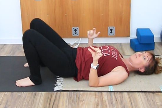 yoga teacher on a yoga mat doing a mini hip bridge